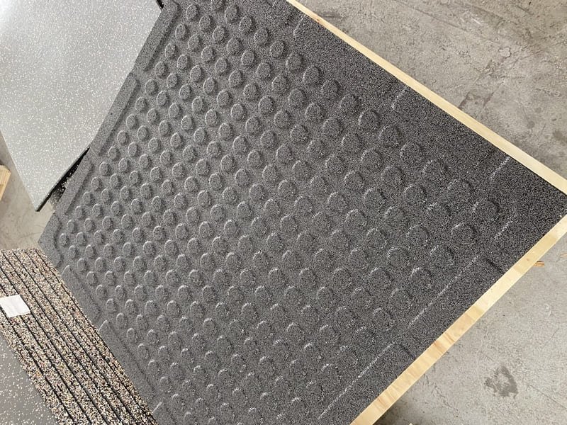 A gym floor showing distinct zones with rubber tiles, LVT, and artificial turf.